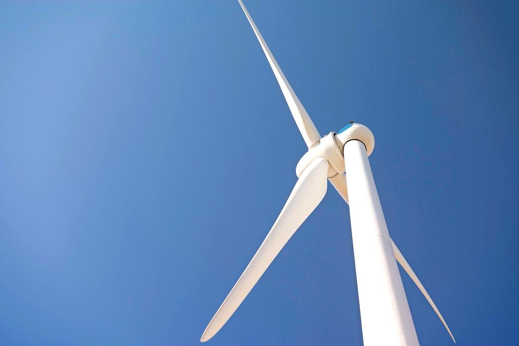 Wind turbines in open field under blue sky